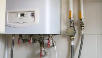 a gas double circuit boiler is installed in the apartment. autonomous heating boiler with a control panel, buttons, a display with temperature readings and red valves on pipes in a home kitchen. a gas double circuit boiler is installed in the apartment. autonomous heating boiler with a control panel, buttons, a display with temperature readings and red valves on pipes in a home kitchen.